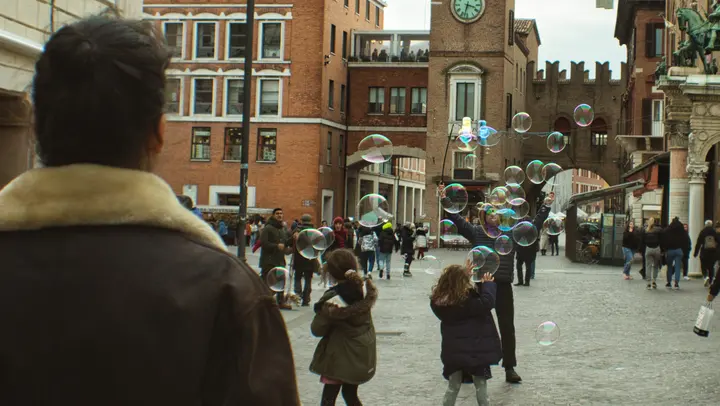 Children reaching for soap bubbles in a piazza