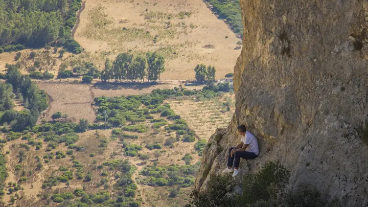 Person sitting on a cliff above a dry valley